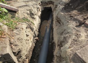 Installing sewer pipe in the ground trench.